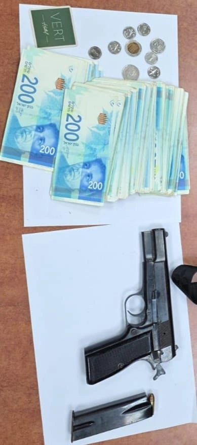 תמונה של שטרות הכסף והאקדח שנתפסו ע"י המשטרה