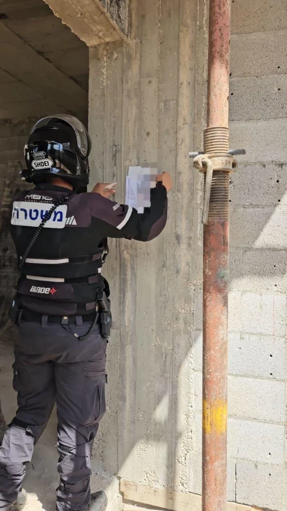 תמונה של שוטר מצמיד את צו הסגירה באתר הבניה