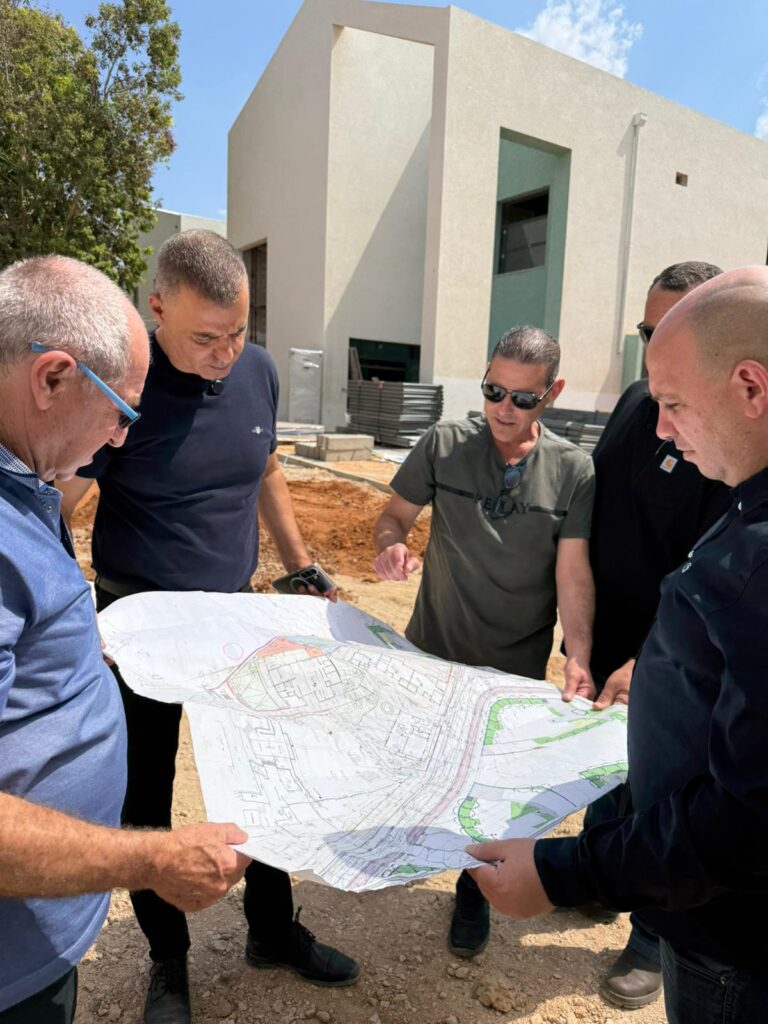 תמונה של בעלי תפקידים אוחזים תכנית בניה
