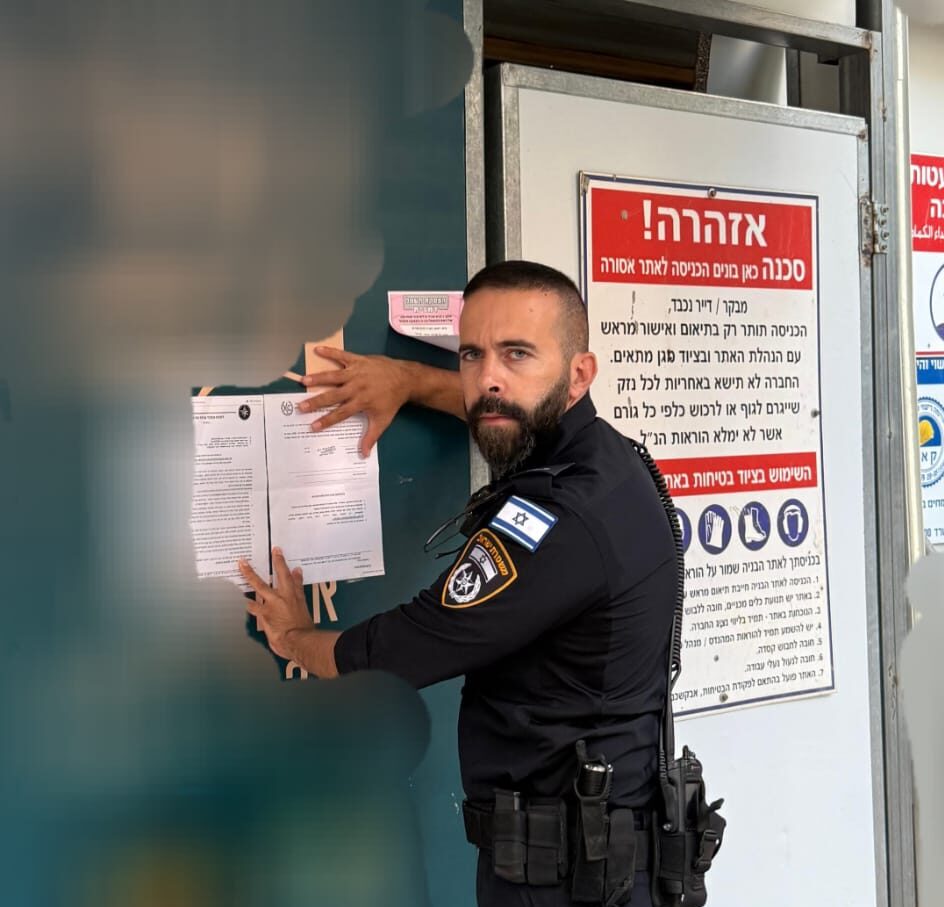 צילום שוטר מצמיד את צו הסגירה על גדר אתר הבניה