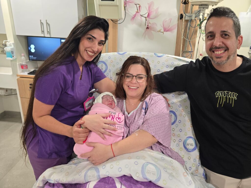 תמונה של הזוג המאושר עם התינוק והמיילדת