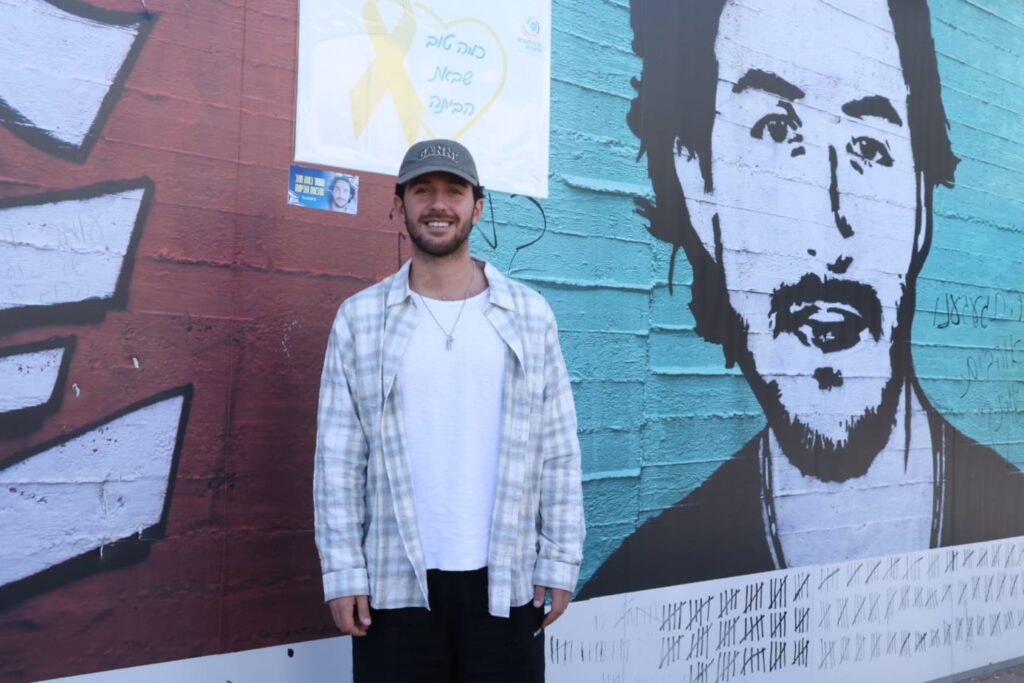 עומר שם טוב ליד קיר בגרפיטי
